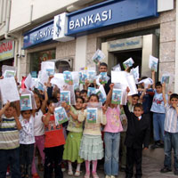 Karnesi ile İş Bankası'na giderek kitap hediyelerini alan öğrenciler şube önünde mutluluk pozu verdi 